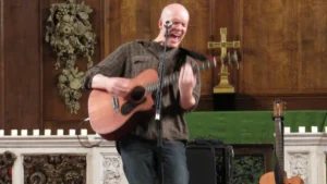 Devin Townsend performing solo with an acoustic guitar in a church